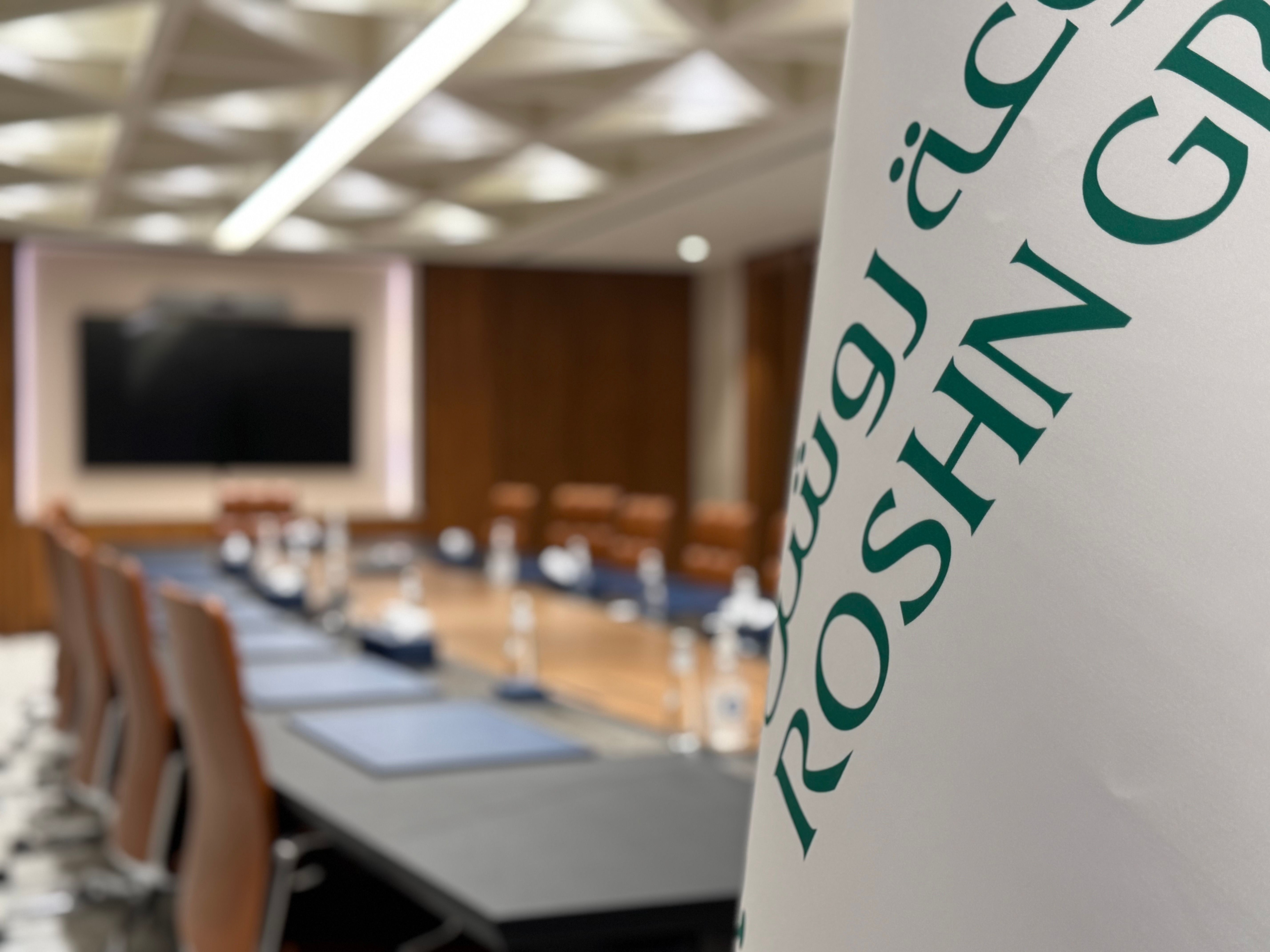 Boardroom with ROSHN logo flag